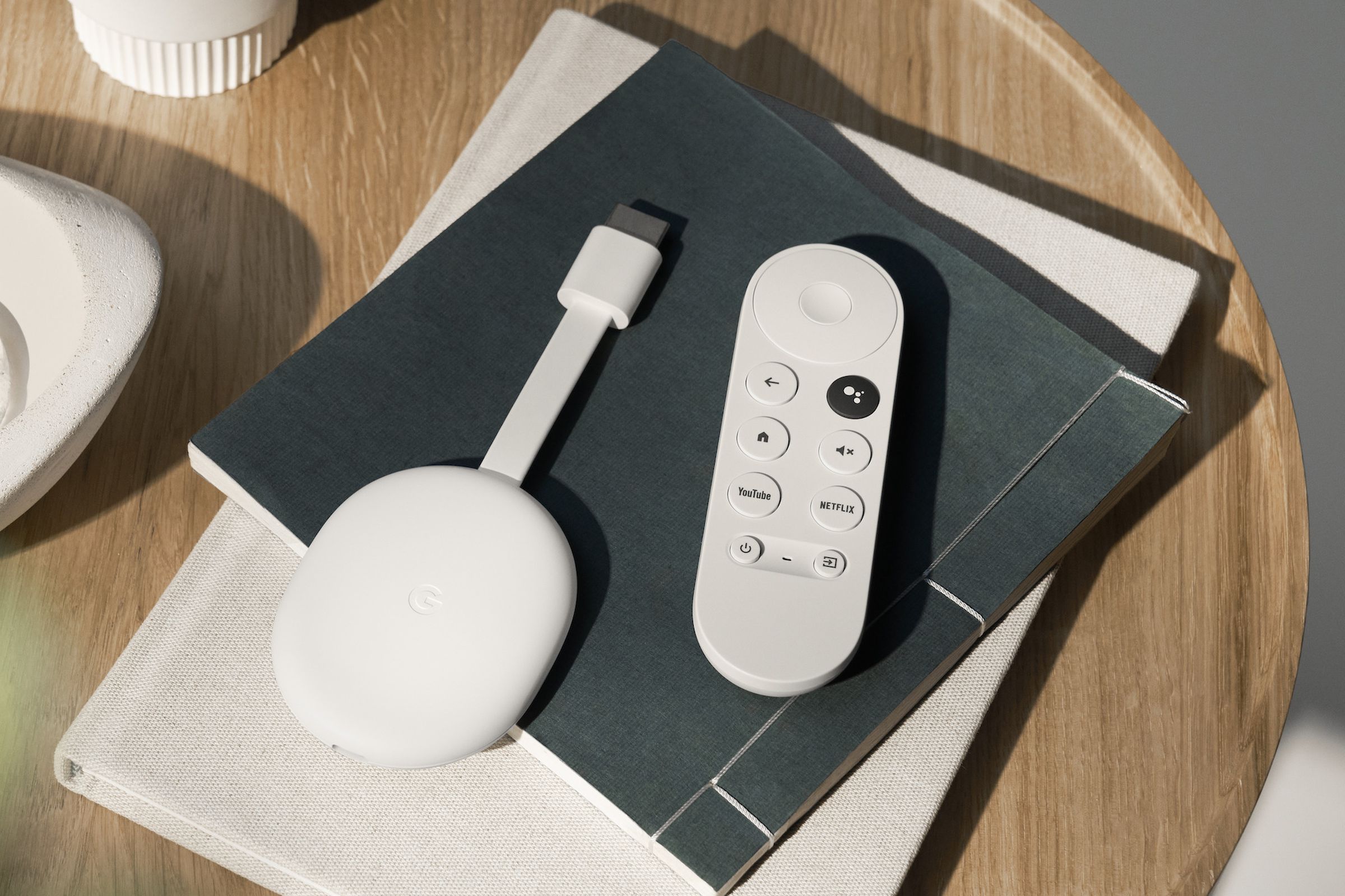 An image of the Chromecast with Google TV HD streaming player on a coffee table.