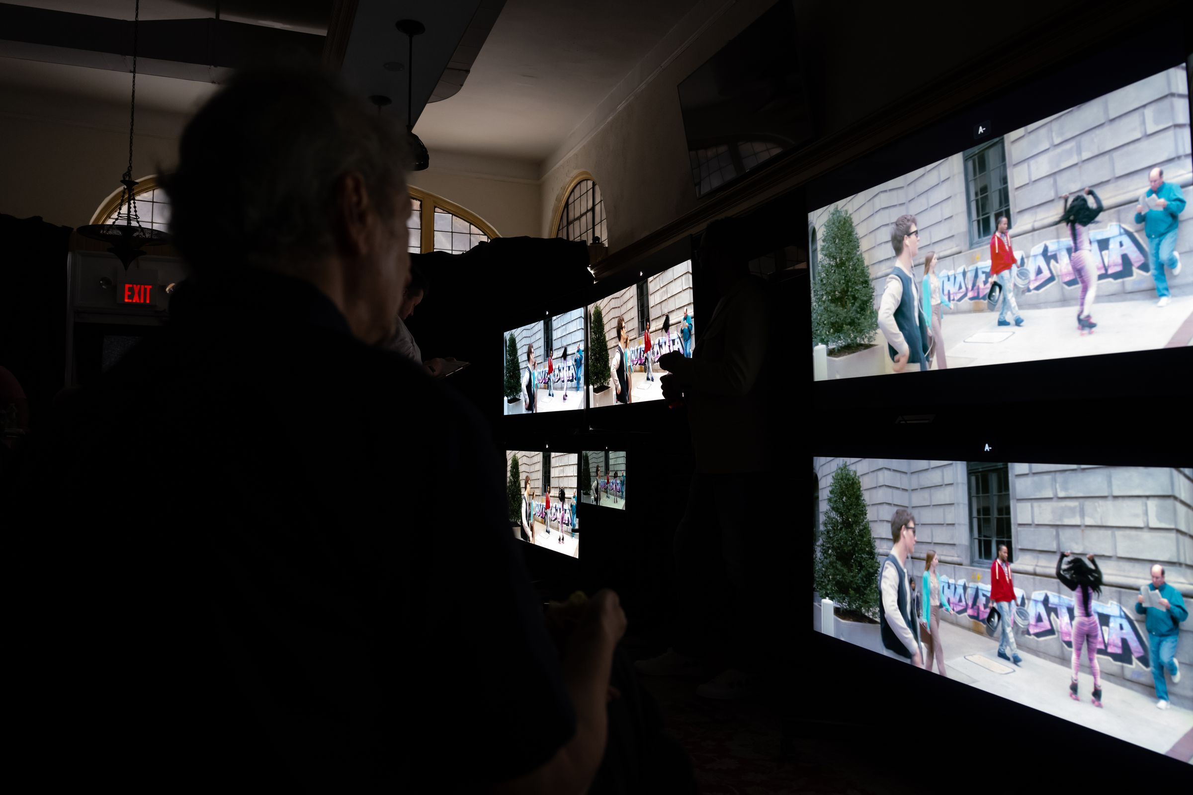 Several large TVs in a dark room showing a scene from Baby Driver.