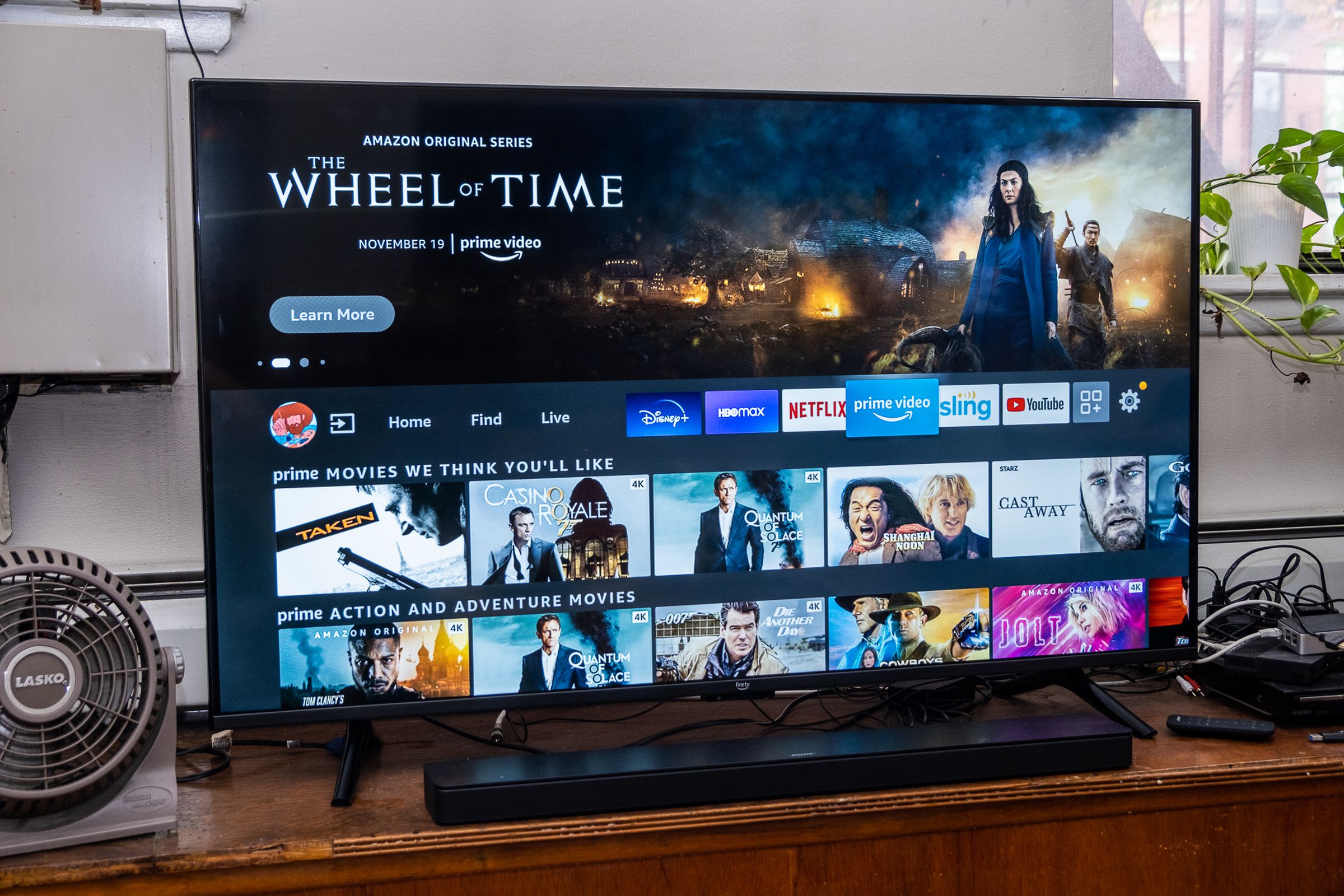 A Fire TV Omni and soundbar on a wood TV stand in a living room.