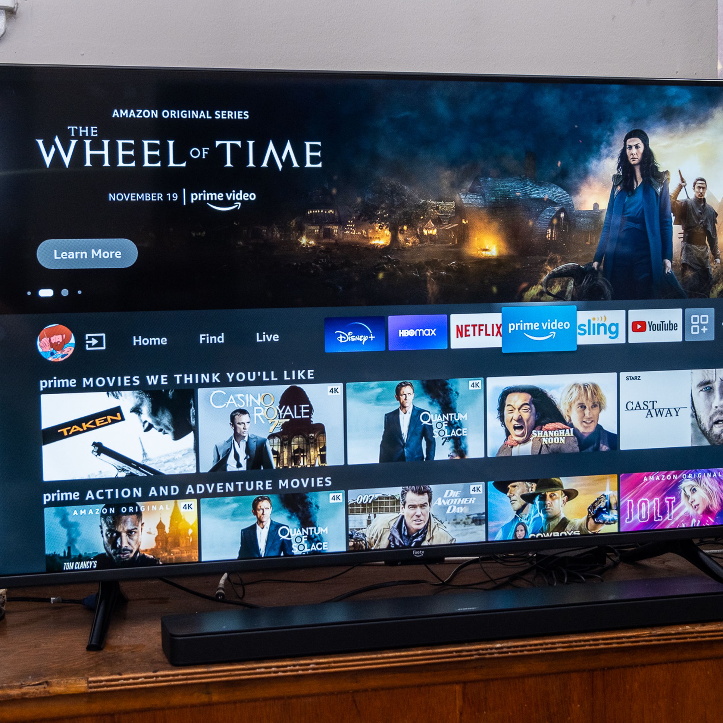 A Fire TV Omni and soundbar on a wood TV stand in a living room.