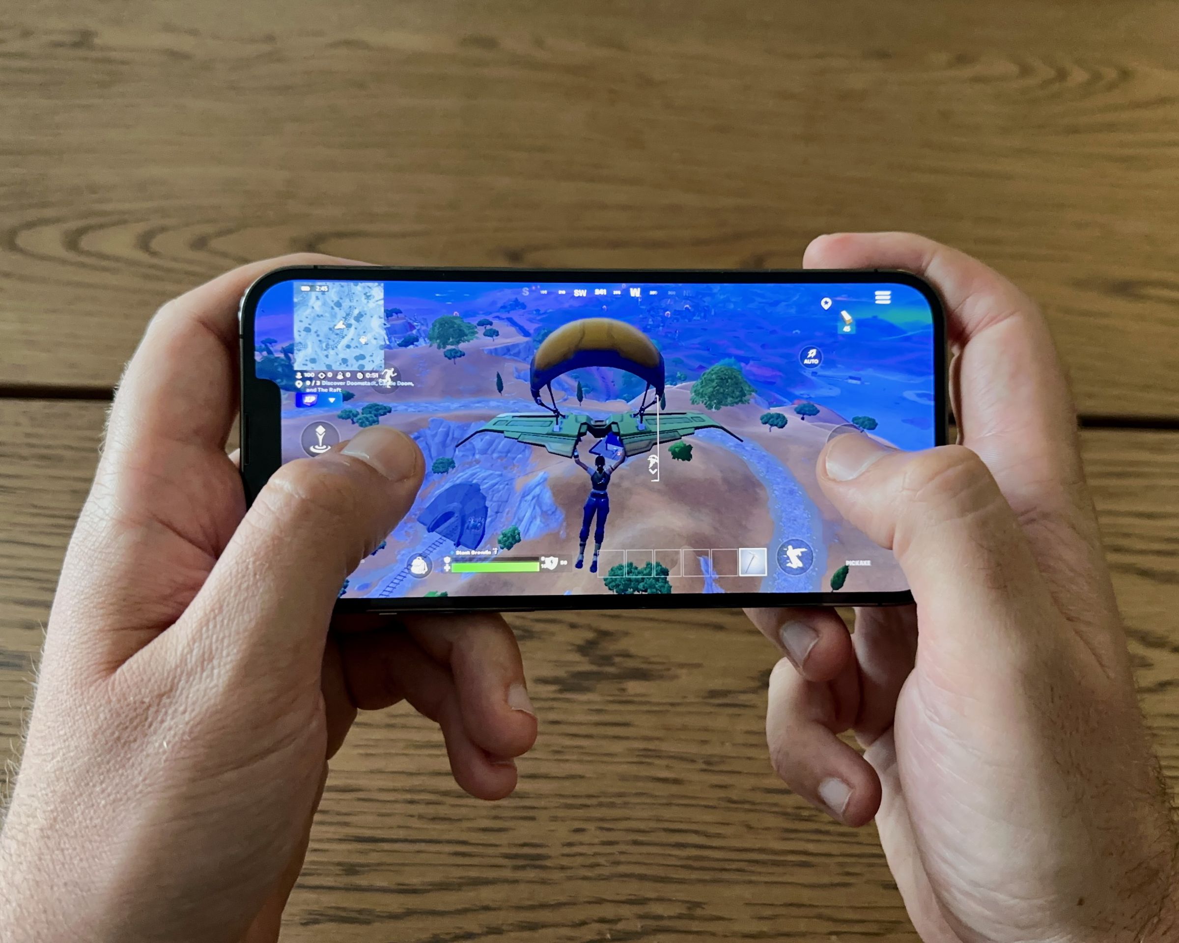 An iPhone being held with two hands playing Fortnite.