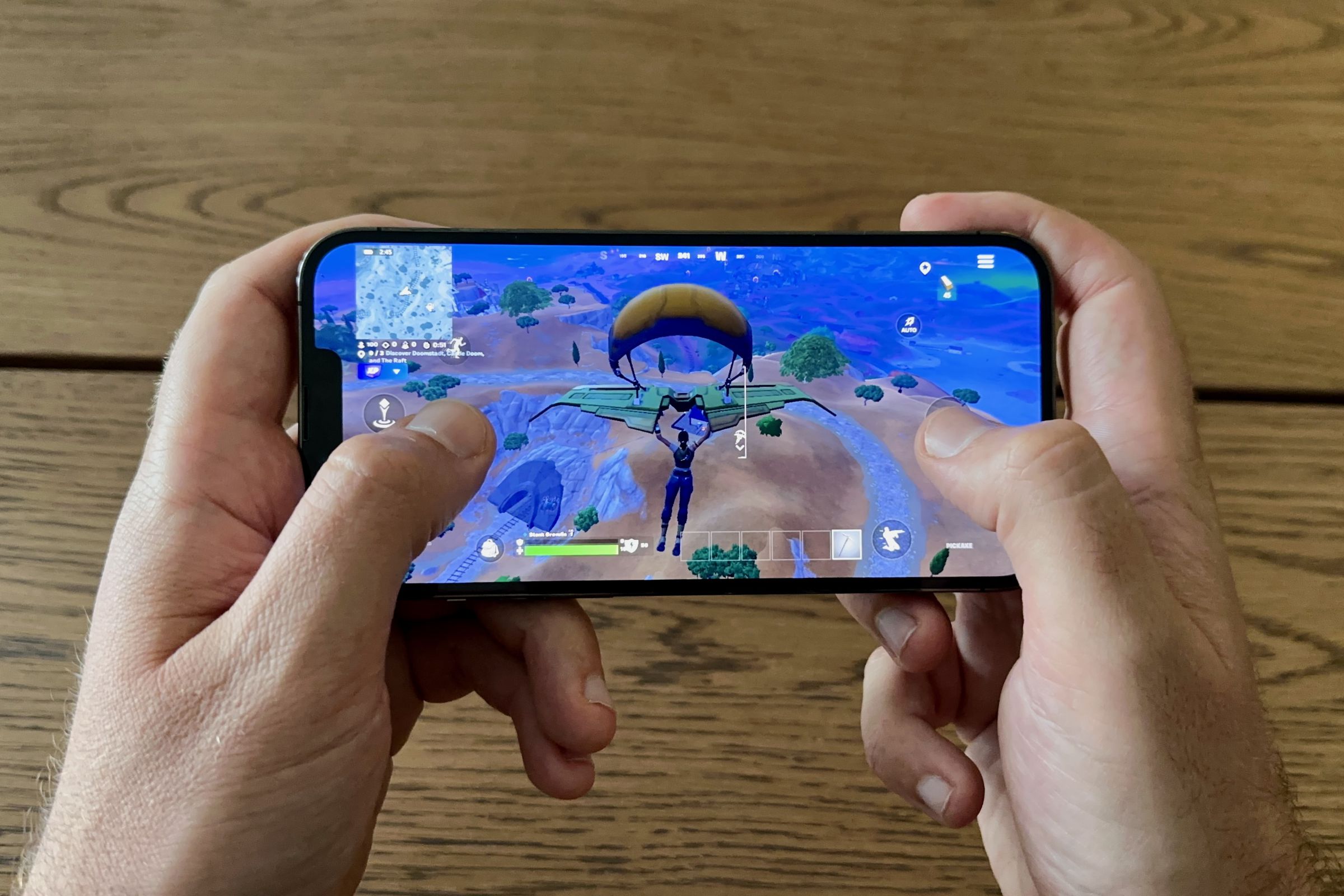 An iPhone being held with two hands playing Fortnite.