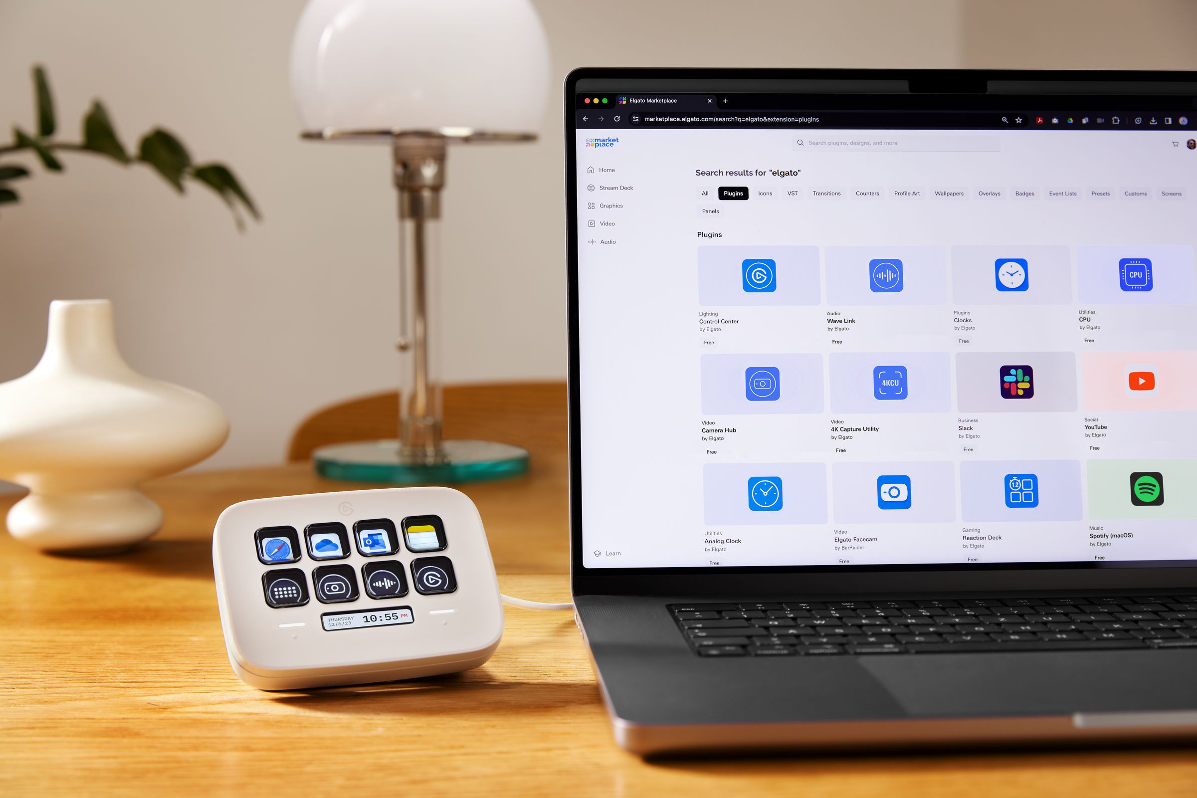 An Elgato Stream Deck Neo plugged into and sitting beside a laptop on a desk.