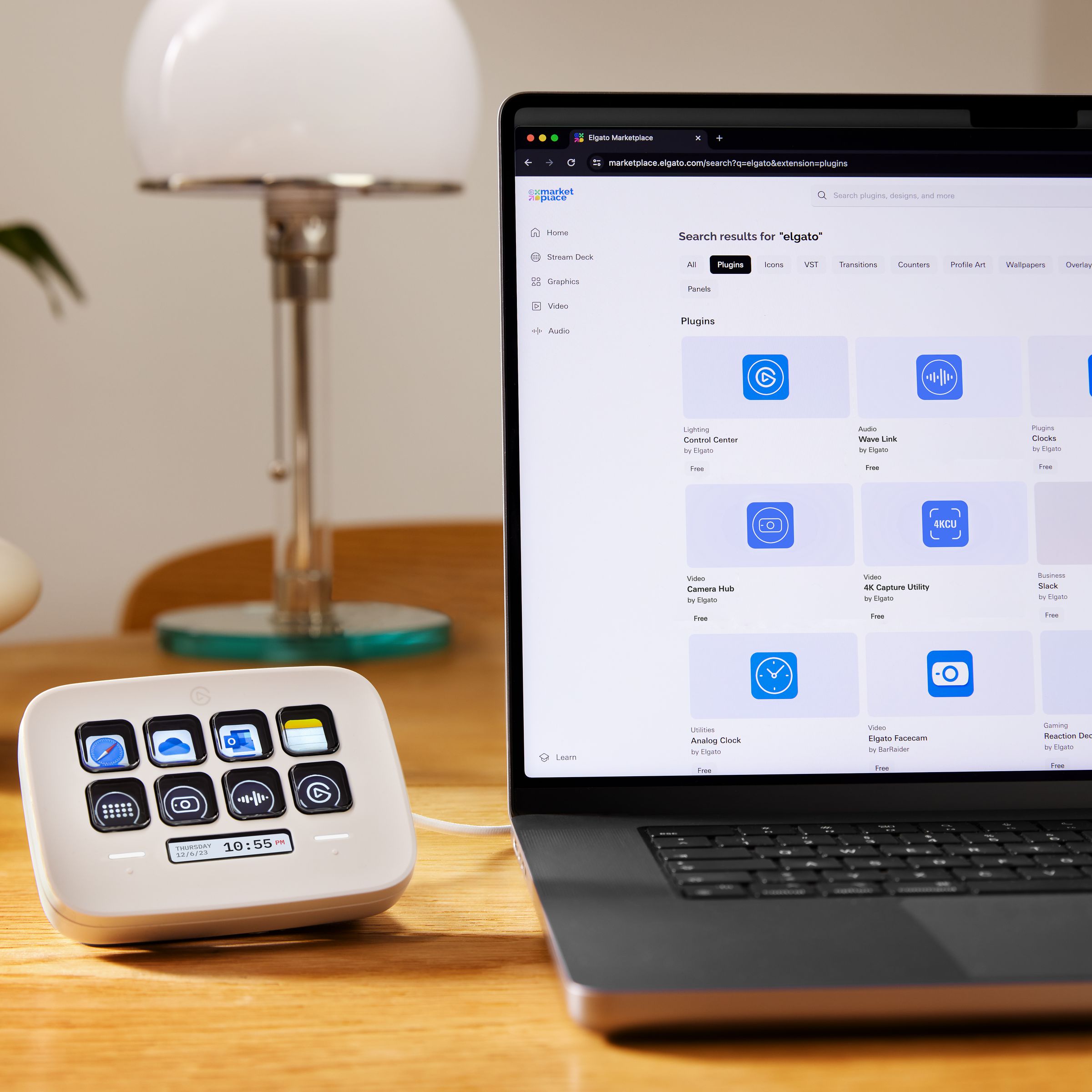 An Elgato Stream Deck Neo plugged into and sitting beside a laptop on a desk.